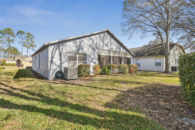 rear view of property with central air condition unit and a lawn