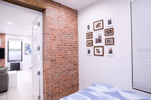 bedroom with radiator heating unit and brick wall