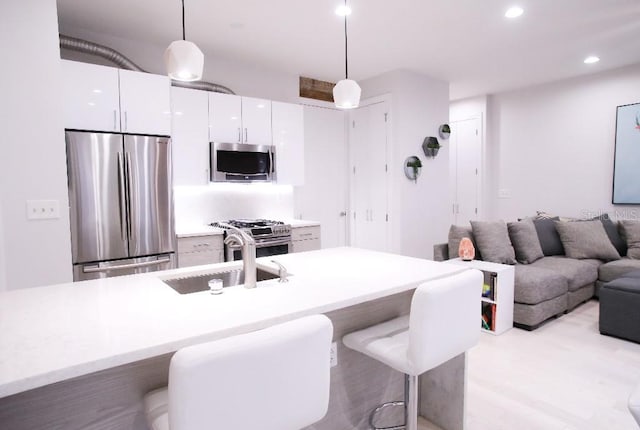 kitchen with appliances with stainless steel finishes, a breakfast bar, pendant lighting, sink, and white cabinets