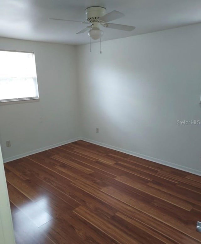 empty room featuring dark wood-type flooring and ceiling fan