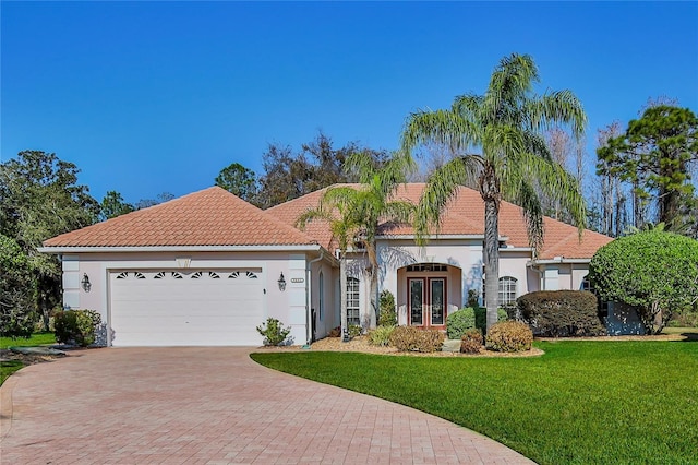 mediterranean / spanish-style house with a garage, a front lawn, and french doors