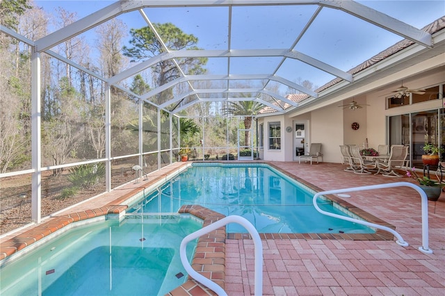 view of swimming pool with ceiling fan, a patio, and glass enclosure