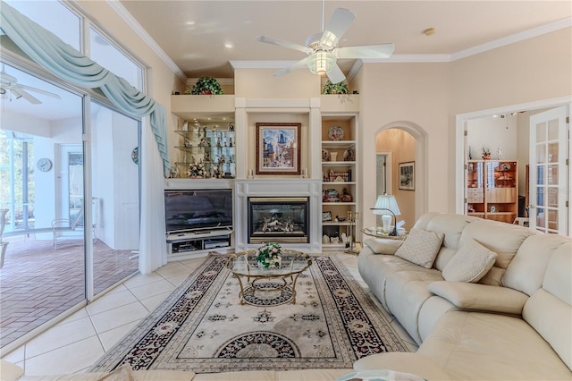 tiled living room with built in shelves, ornamental molding, and ceiling fan