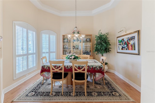 dining room featuring an inviting chandelier, wood-type flooring, and a tray ceiling