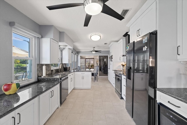 kitchen with stainless steel appliances, dark stone countertops, white cabinets, and kitchen peninsula