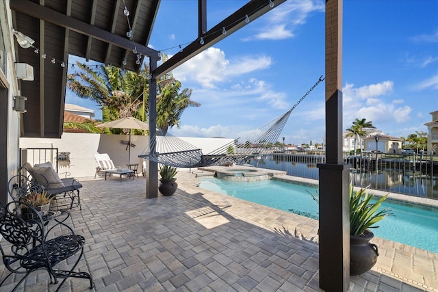 view of swimming pool with a patio area, a water view, and an in ground hot tub