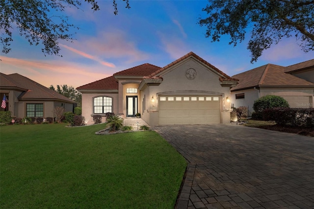 mediterranean / spanish-style home with a garage and a yard