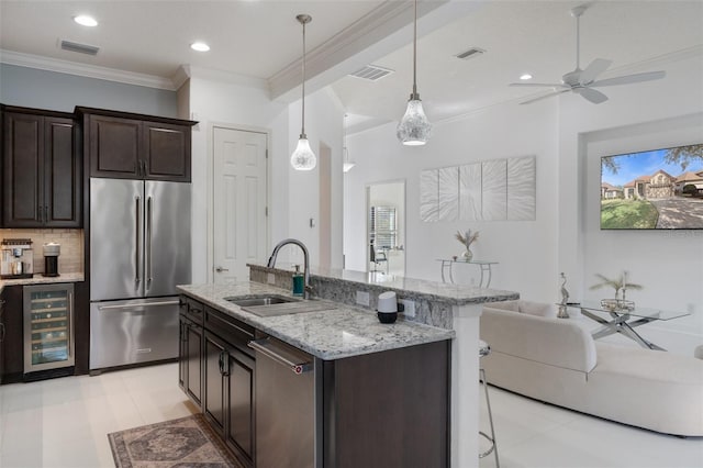 kitchen with appliances with stainless steel finishes, sink, wine cooler, hanging light fixtures, and dark brown cabinets