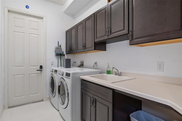 clothes washing area with cabinets, light tile patterned floors, sink, and washing machine and clothes dryer