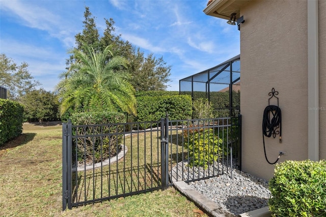 view of gate featuring glass enclosure and a lawn