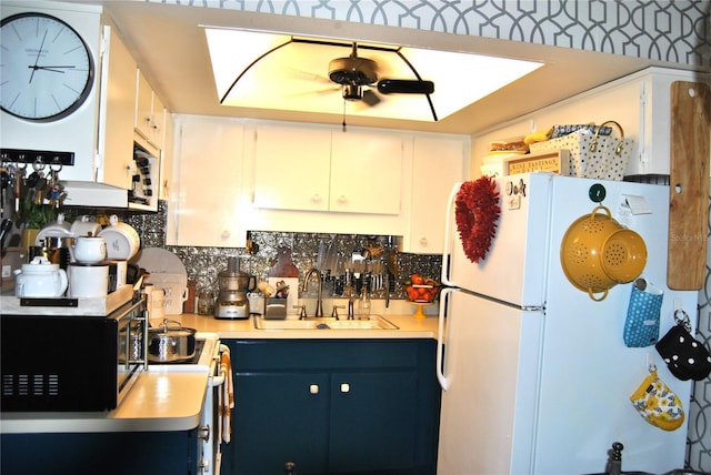 kitchen with white refrigerator, sink, decorative backsplash, and white cabinets