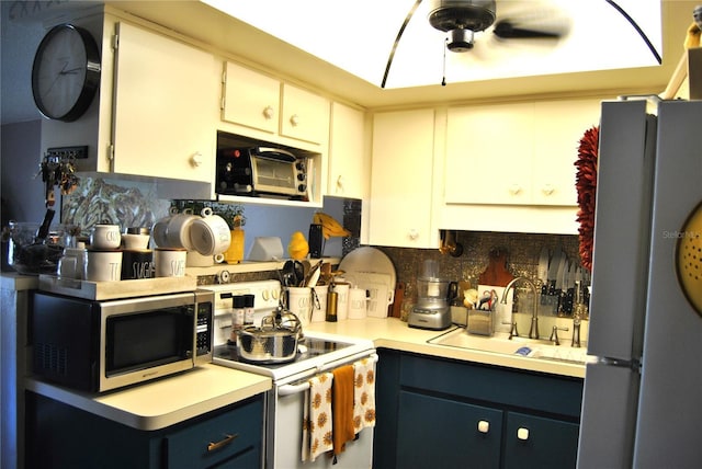 kitchen featuring appliances with stainless steel finishes, tasteful backsplash, white cabinetry, sink, and blue cabinetry