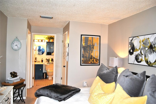 bedroom featuring ensuite bath and a textured ceiling