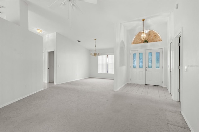 carpeted entrance foyer featuring ceiling fan with notable chandelier and vaulted ceiling