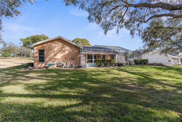 rear view of property with glass enclosure and a lawn