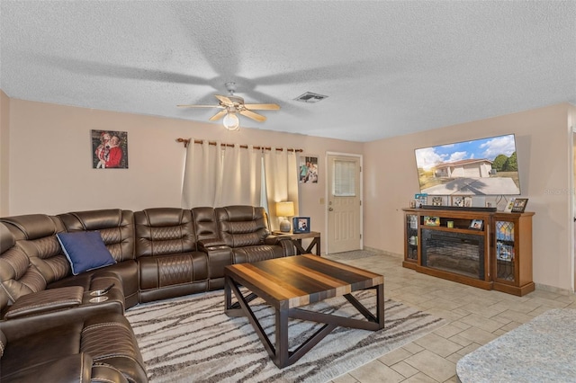 living room with ceiling fan and a textured ceiling