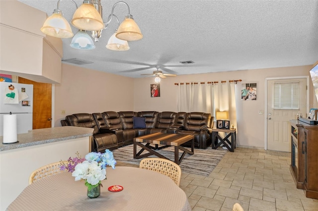 living room with ceiling fan with notable chandelier and a textured ceiling