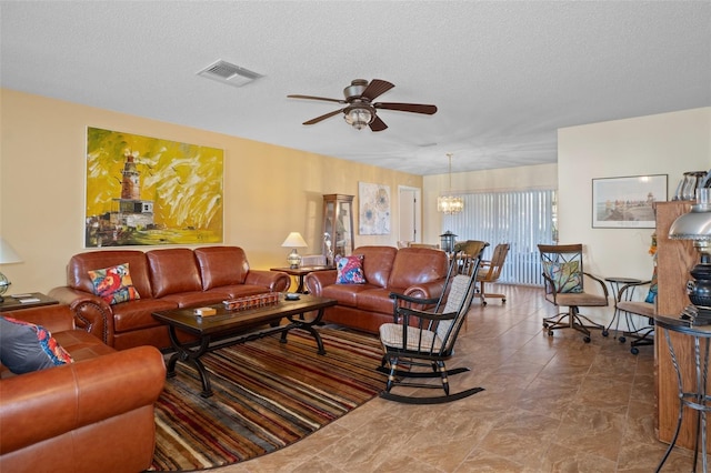 living room with ceiling fan with notable chandelier and a textured ceiling