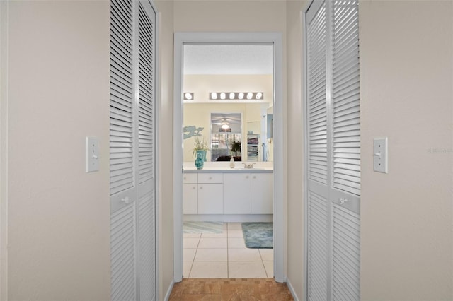 hall featuring light tile patterned flooring and sink