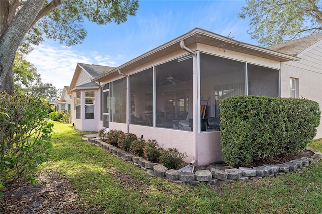 view of home's exterior with a sunroom and a yard