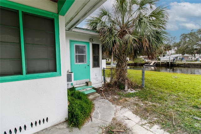 view of exterior entry featuring a water view and a yard