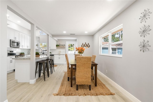 dining space with plenty of natural light, sink, and light hardwood / wood-style flooring