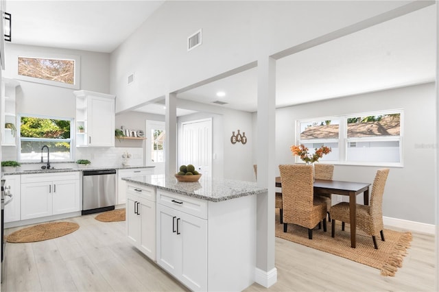 kitchen featuring light stone counters, stainless steel dishwasher, sink, and white cabinets