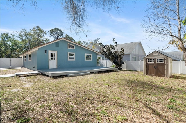 rear view of house featuring a wooden deck, a yard, and a storage shed