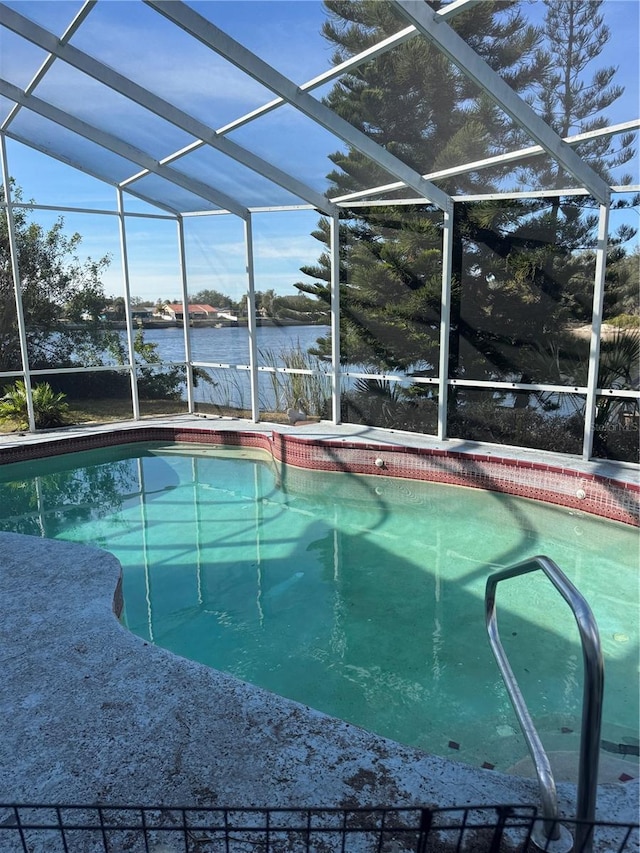 view of pool featuring glass enclosure and a water view