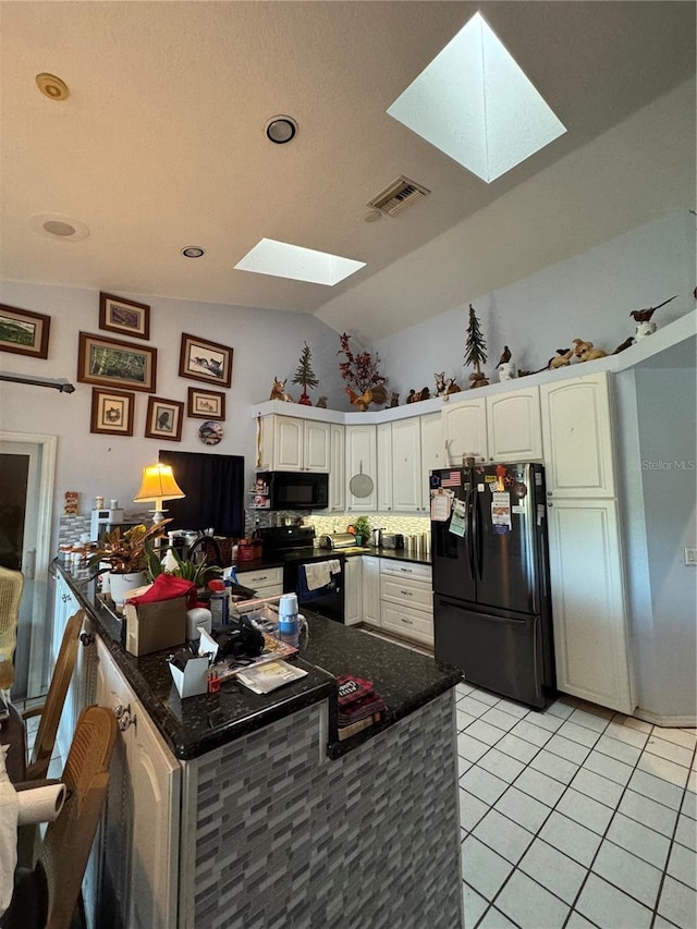 kitchen with vaulted ceiling with skylight, black appliances, white cabinets, and light tile patterned flooring