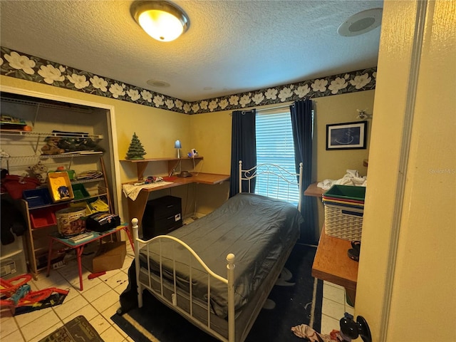 bedroom with tile patterned flooring, a closet, and a textured ceiling