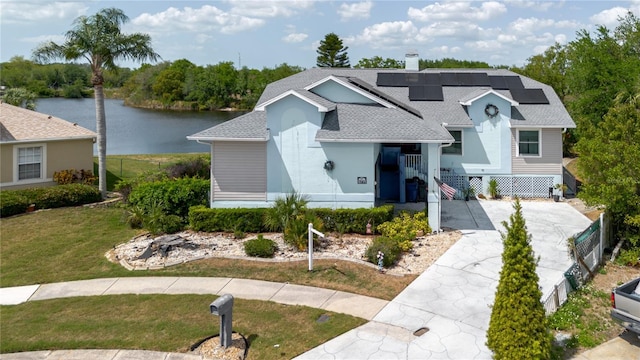 5771 Catskill Rd, Holiday, FL 34690 - view of front facade with roof with shingles, a chimney, a front yard, solar panels, and a water view