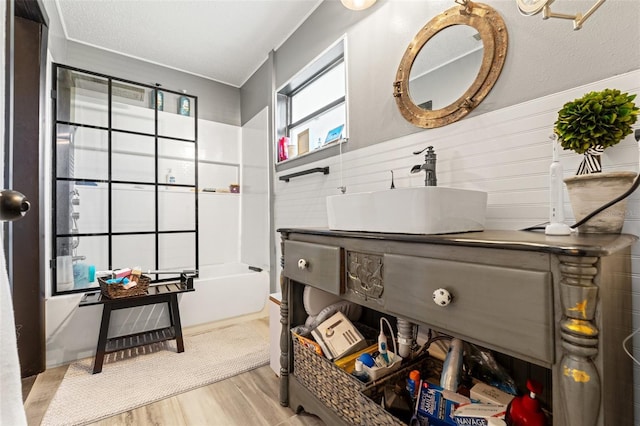 interior space with light wood-style floors, a sink, and a wainscoted wall