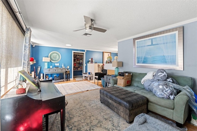 living area featuring a ceiling fan, visible vents, a textured ceiling, and wood finished floors