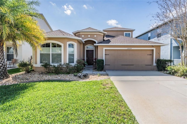 mediterranean / spanish-style house featuring concrete driveway, a front yard, an attached garage, and stucco siding