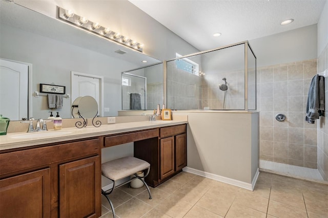 full bathroom with double vanity, a sink, a textured ceiling, a walk in shower, and tile patterned flooring