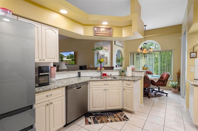 kitchen with sink, decorative light fixtures, appliances with stainless steel finishes, kitchen peninsula, and light stone countertops