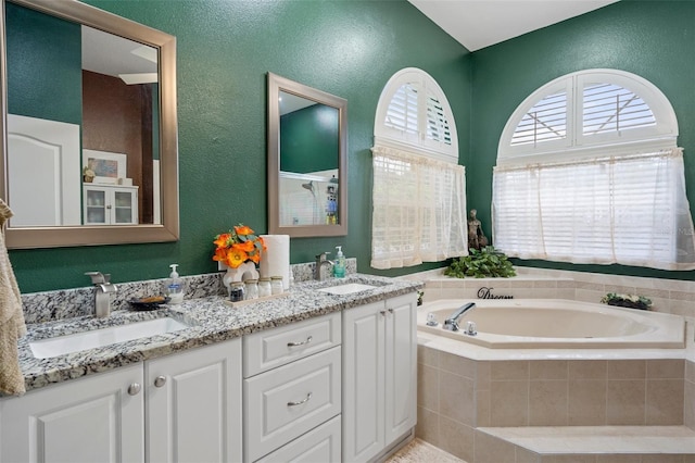 bathroom featuring vanity and tiled bath