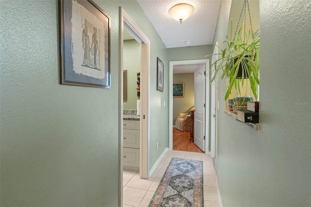 corridor featuring light tile patterned floors and a textured ceiling