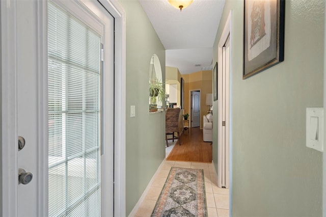 hall featuring plenty of natural light and light tile patterned flooring