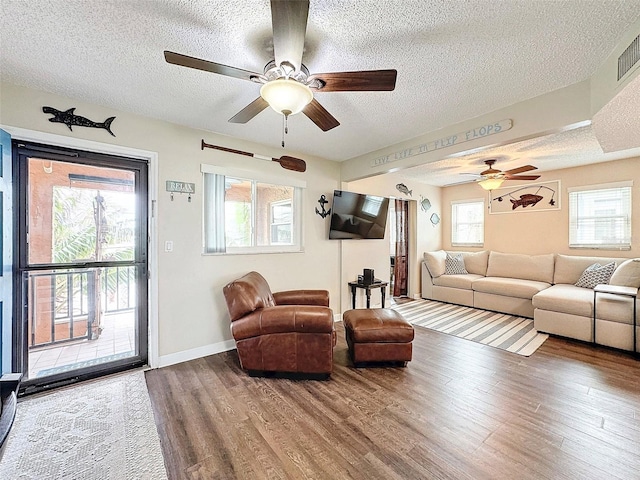 living room with hardwood / wood-style floors, a textured ceiling, and ceiling fan