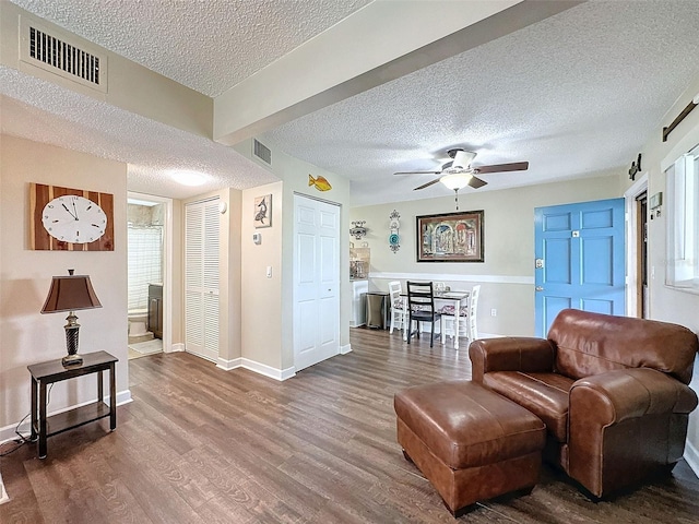 living room with ceiling fan, a barn door, hardwood / wood-style floors, and a textured ceiling