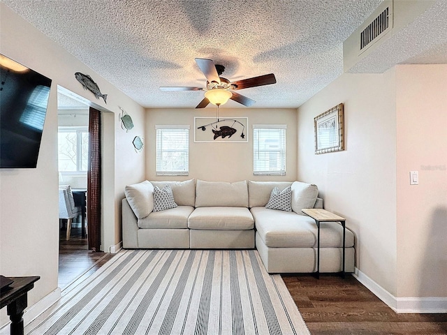 living room featuring ceiling fan, dark hardwood / wood-style floors, and a textured ceiling