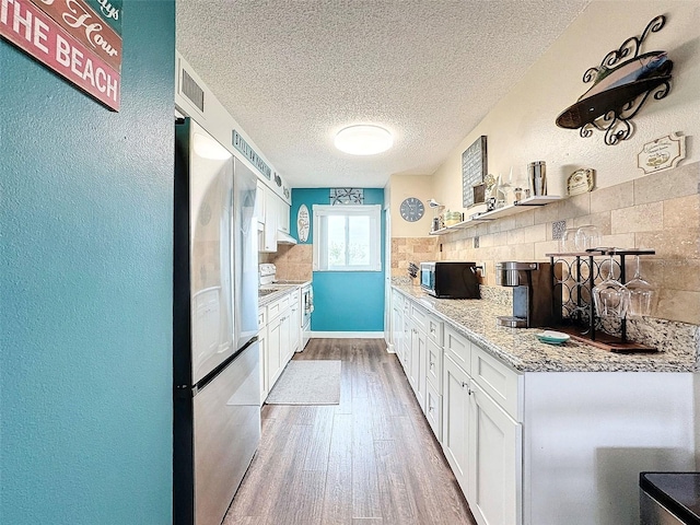 kitchen featuring tasteful backsplash, stainless steel fridge, hardwood / wood-style floors, and white cabinets