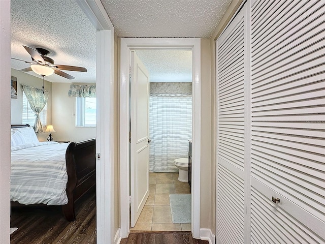 bedroom featuring a closet, ensuite bathroom, hardwood / wood-style floors, and a textured ceiling