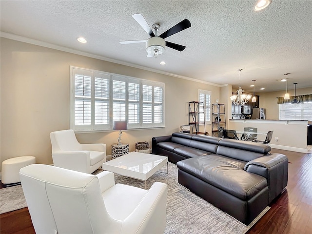 living room with a textured ceiling, dark wood-style flooring, ceiling fan with notable chandelier, and crown molding