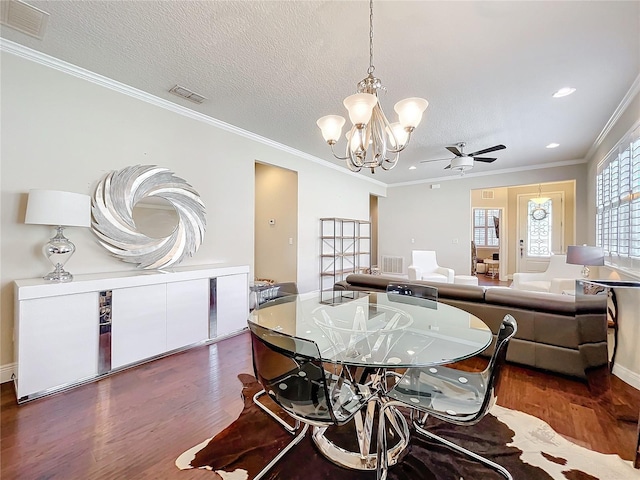 dining area featuring dark wood-style floors, visible vents, crown molding, and a textured ceiling