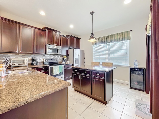 kitchen with beverage cooler, decorative backsplash, a kitchen island, hanging light fixtures, and stainless steel appliances