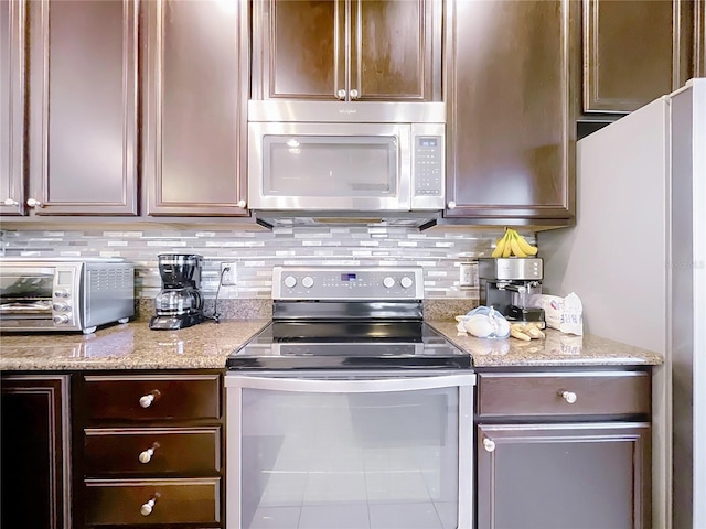 kitchen featuring a toaster, light stone counters, stainless steel appliances, and backsplash