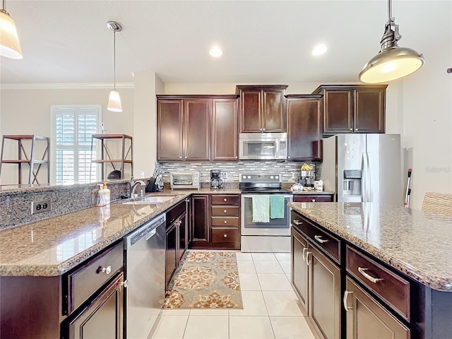 kitchen featuring light tile patterned floors, stainless steel appliances, a sink, tasteful backsplash, and decorative light fixtures